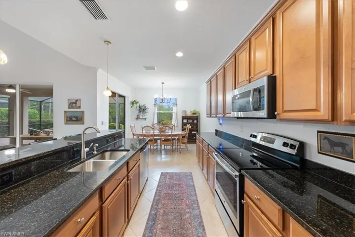 Kitchen with stainless steel appliances, plenty of natural light, hanging light fixtures, brown cabinets, and recessed lighting