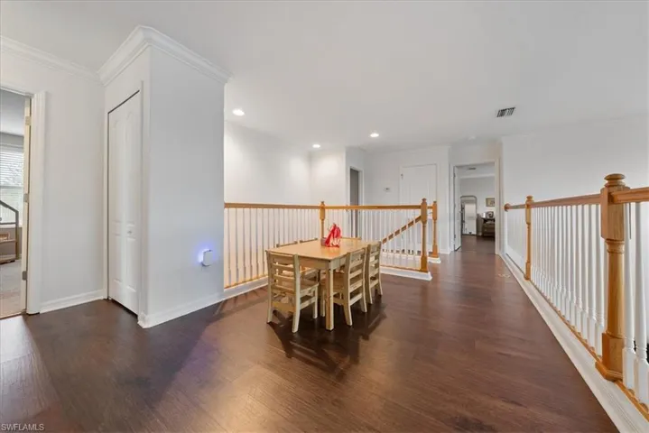 Dining room with dark wood-style floors, crown molding, and recessed lighting