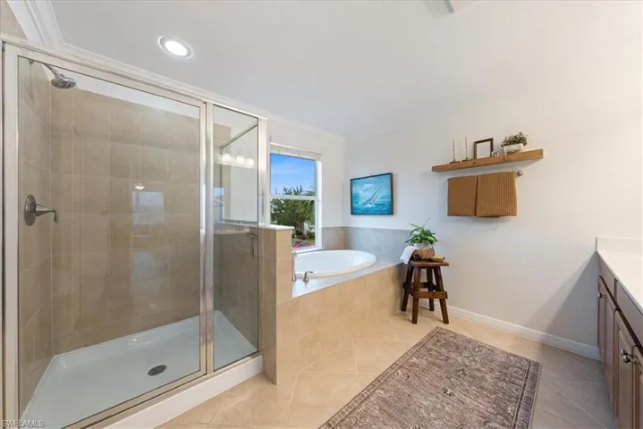 Bathroom with vanity, tile patterned floors, a shower stall, a bath, and ornamental molding