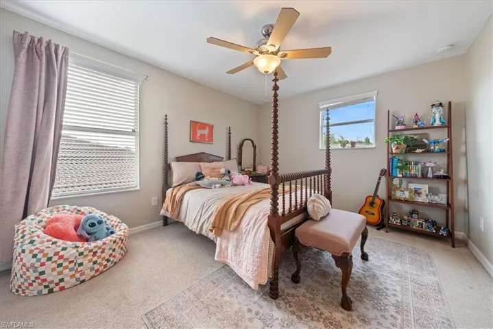 Carpeted bedroom with ceiling fan and baseboards