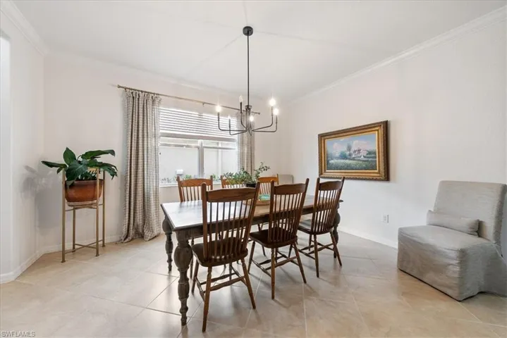 Dining space featuring ornamental molding, a chandelier, and light tile patterned flooring