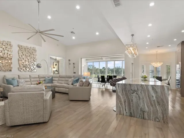 Open Concept, Spacious Living room with modern ceiling fan, Vaulted ceiling, wood floors, and access to the dining area and lovely views of the golf course and lake