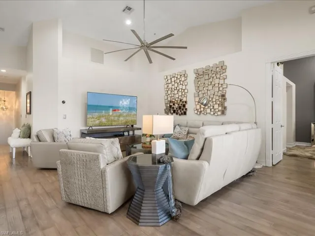 Spacious Living room featuring wood floors, modern ceiling fan, and lovely vaulted ceiling