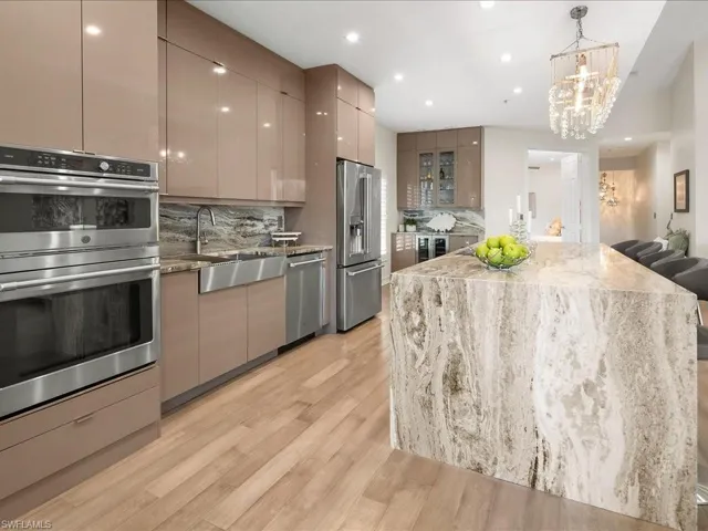 Kitchen featuring European cabinets, Striking chandelier, 10 ft island with quartz waterfall & countertops, storage on both sides,  a kitchen breakfast bar, GE Café appliances including a Keurig in the refrigerator