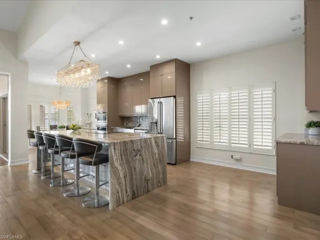 Kitchen featuring Striking chandelier, 10 ft island with quartz waterfall & countertops, storage on both sides,  a kitchen breakfast bar, GE Café appliances including a Keurig in the refrigerator