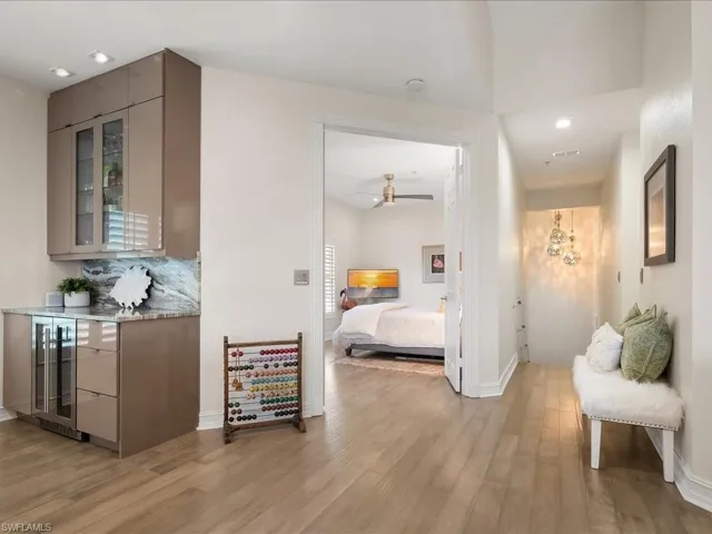 Bar area, looking to Guest Bedroom #1 and stairwell, featuring wine cooler, light wood-flooring, and recessed lighting