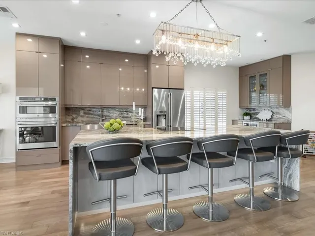 Kitchen featuring European Cabinets, Striking chandelier, 10 ft island with quartz waterfall & countertops, storage on both sides,  a kitchen breakfast bar, GE Café appliances including a Keurig in the refrigerator