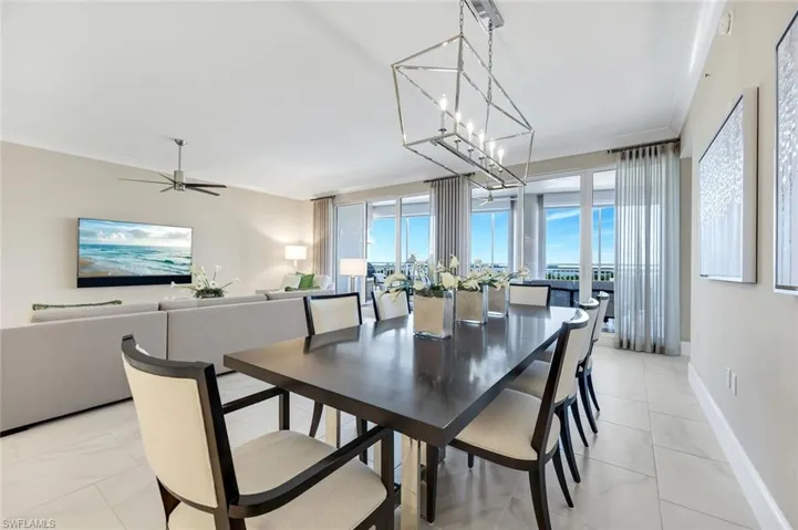 Formal dining area framed by custom lighting and floor-to-ceiling windows, with beautiful views and plenty of space to host unforgettable dinners!