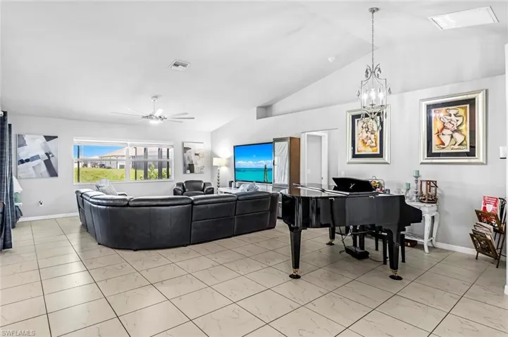 Living room with ceiling fan with notable chandelier and lofted ceiling