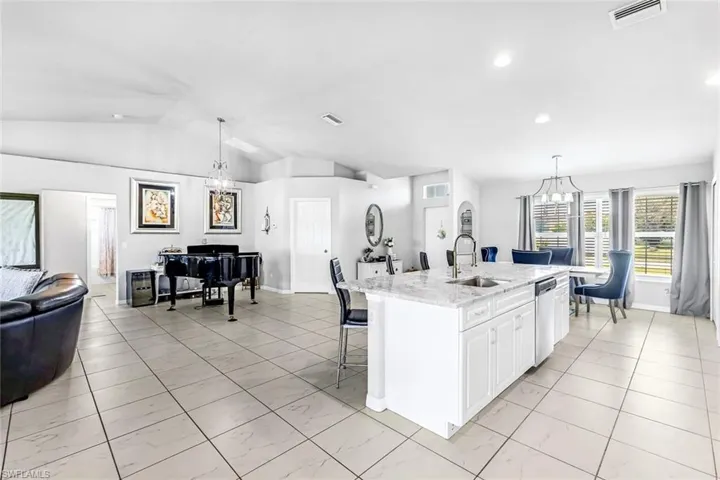 Kitchen featuring a center island with sink, dishwasher, sink, and decorative light fixtures