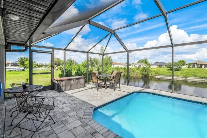 View of pool with a water view, a lanai, a patio, and a hot tub