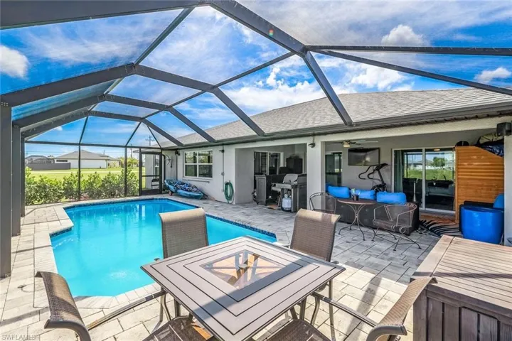 View of swimming pool with glass enclosure, area for grilling, and a patio area