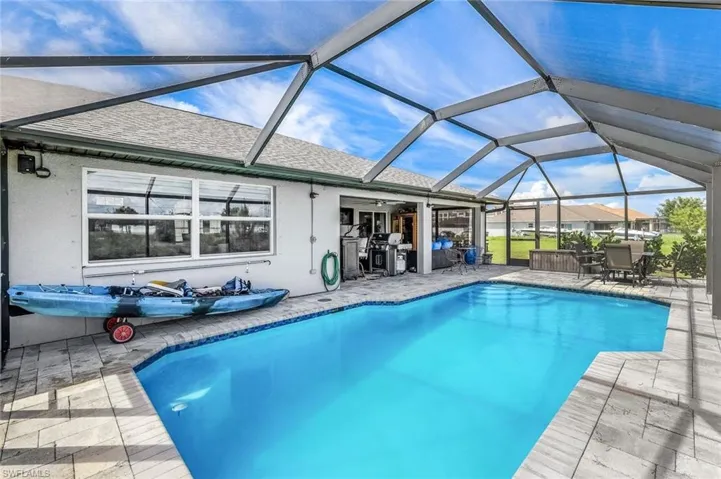 View of pool with glass enclosure and a patio