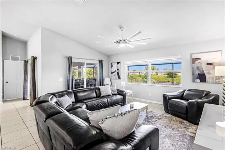 Living room with lofted ceiling, ceiling fan, and a wealth of natural light