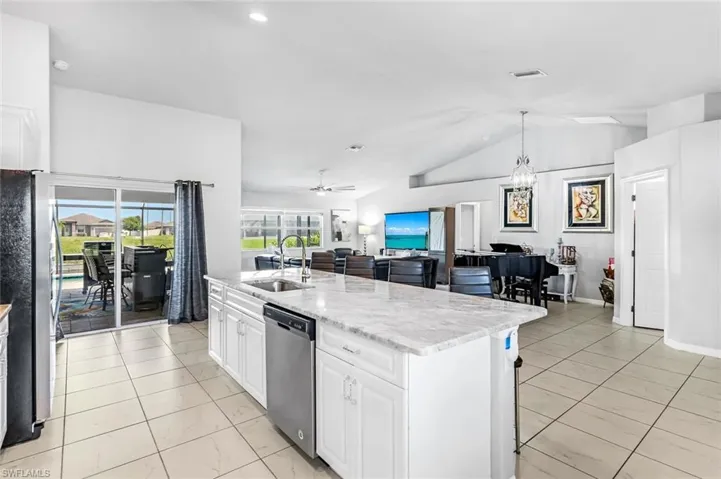 Kitchen featuring ceiling fan with notable chandelier, sink, appliances with stainless steel finishes, lofted ceiling, and white cabinets