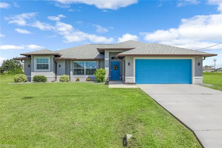 Ranch-style home featuring a garage and a front lawn