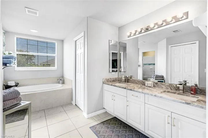 Bathroom with tile patterned floors, tiled bath, and vanity