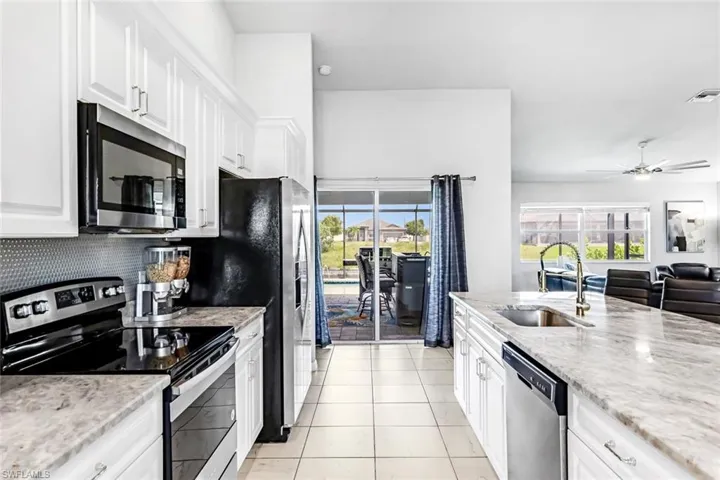 Kitchen featuring appliances with stainless steel finishes, white cabinetry, a healthy amount of sunlight, and sink