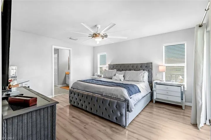 Bedroom featuring ceiling fan, light wood-type flooring, and connected bathroom