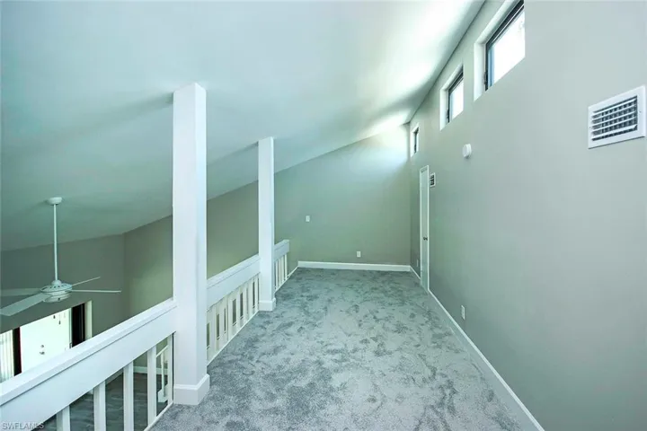 Loft with a high ceiling and light colored carpet