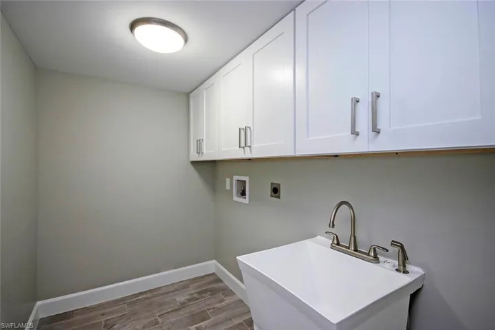 Washroom featuring sink, cabinets, hardwood / wood-style flooring, hookup for a washing machine, and hookup for an electric dryer