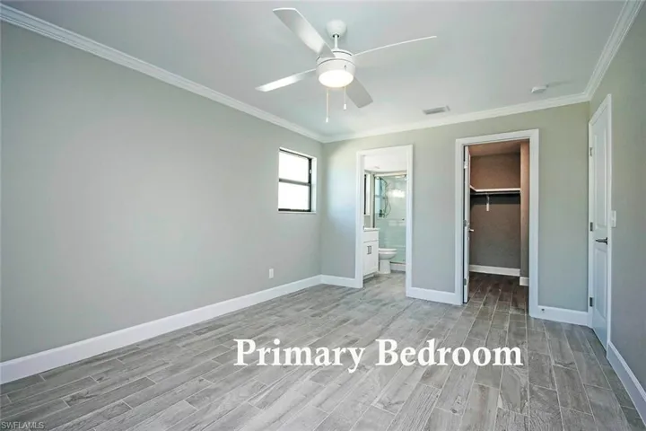 crown molding, a walk in closet, ensuite bath, a closet, and ceiling fan