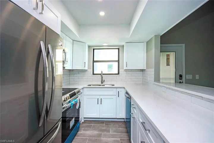 Kitchen featuring white cabinetry, sink, decorative backsplash, and stainless steel appliances
