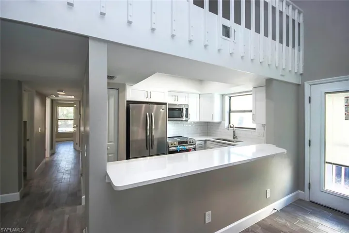 Kitchen with sink, stainless steel appliances, kitchen peninsula, and white cabinets