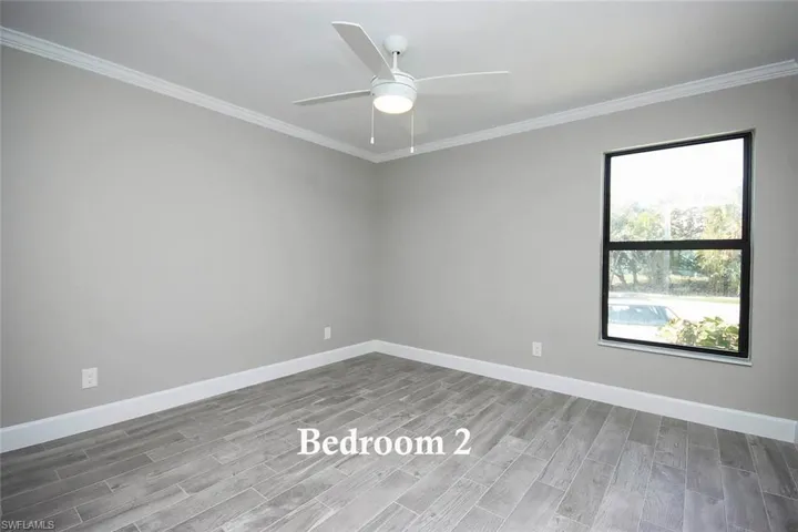 Guest Bedroom - Unfurnished with vinyl wood plank flooring, ornamental molding, and ceiling fan