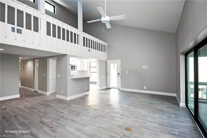 Unfurnished living room featuring ceiling fan and high vaulted ceiling