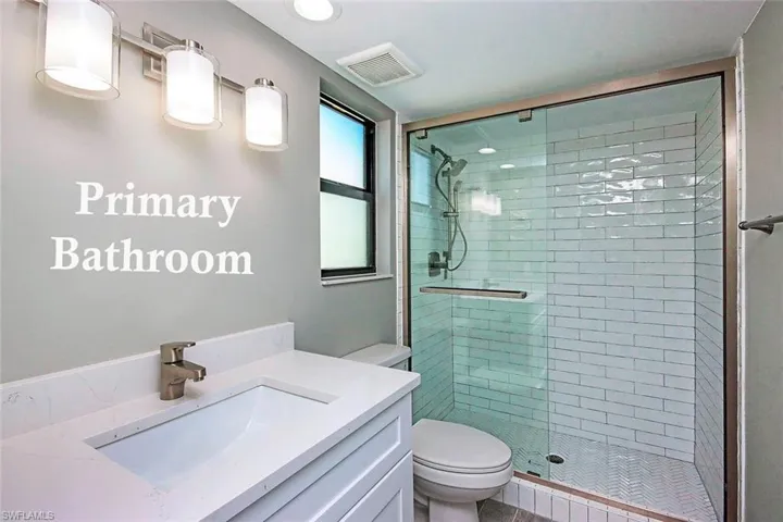 Bathroom featuring vanity, toilet, and an enclosed shower