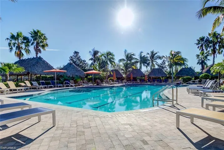 Lap Pool = Expansive swimming pool with lane markers, surrounded by paver decking, multiple thatched-roof cabanas