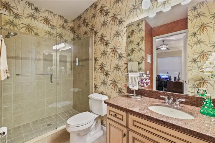 Full bath featuring wallpapered walls, vanity, a ceiling fan, ensuite bathroom, and a shower stall