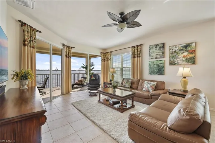 Living area with a water view, light tile patterned floors, and ceiling fan