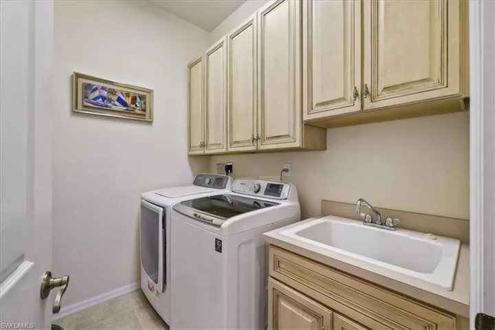 Laundry area with washer and clothes dryer, cabinet space, and light tile patterned floors