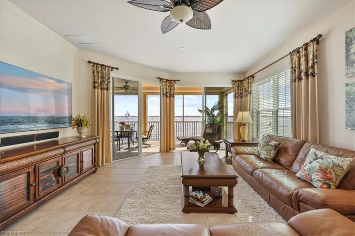Living area with a ceiling fan, light tile patterned floors, and a water view