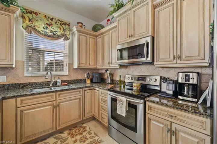 Kitchen with stainless steel appliances, dark stone counters, tasteful backsplash, and light tile patterned flooring