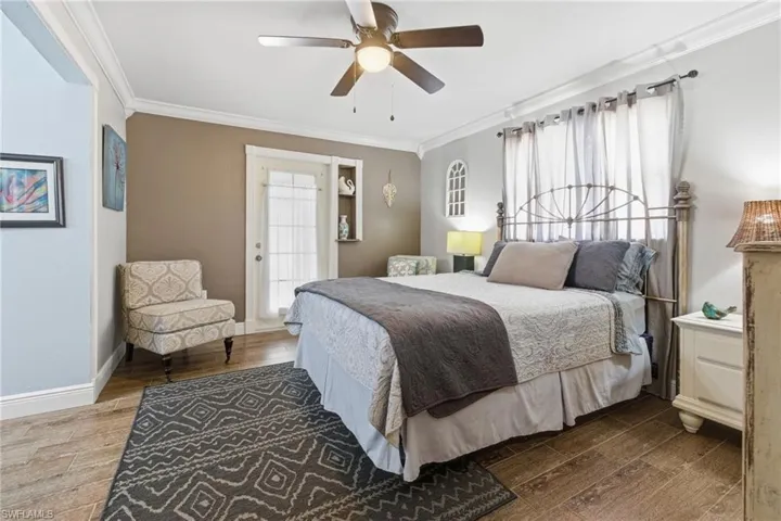 Bedroom with ornamental molding, wood-like tile finished floors, a ceiling fan, and ensuite bathroom