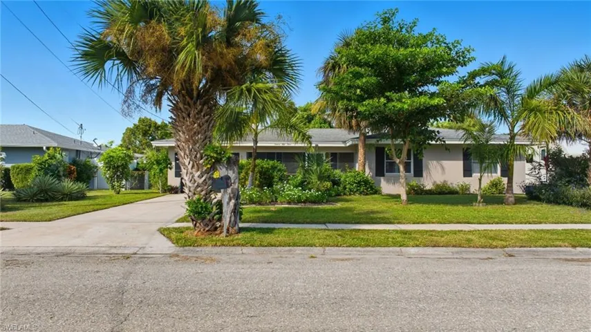 View of front of home featuring a front yard, concrete driveway, sidewalks and stucco siding