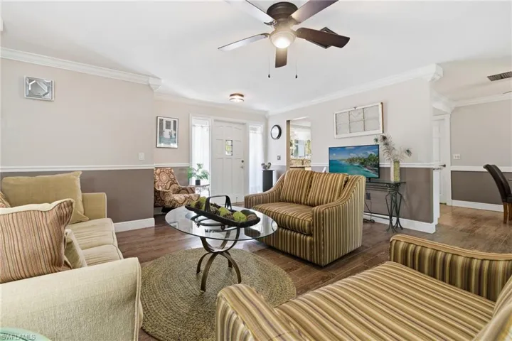Living area with crown molding, wood-look tile flooring, and ceiling fan