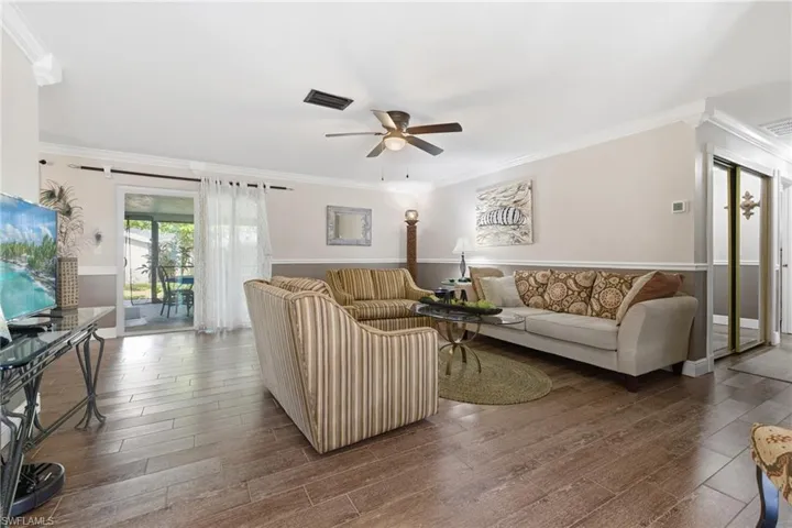 Living area with crown molding, wood-look tile flooring, and ceiling fan