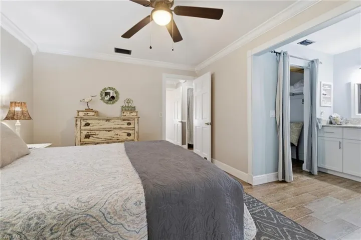 Bedroom with ornamental molding, wood-like tile finished floors, a ceiling fan, and ensuite bathroom