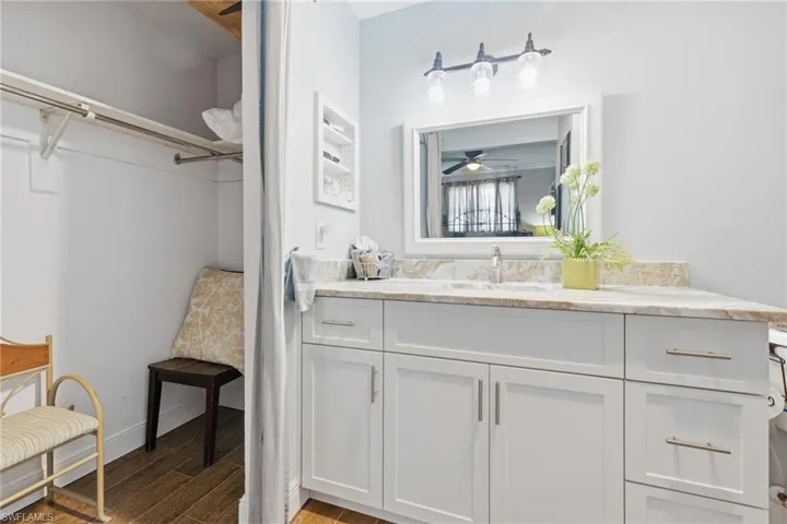 Full bathroom featuring dark wood-like tile flooring, vanity with Granite Countertop, a walk in closet, and a walk-in shower