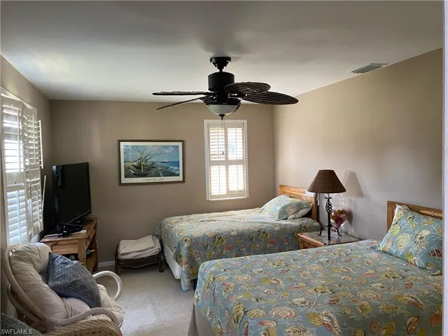 Carpeted bedroom featuring a ceiling fan and baseboards