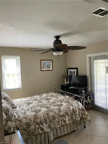 Bedroom featuring multiple windows, light tile patterned floors, and ceiling fan