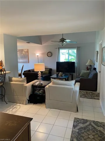 Living room with light tile patterned floors and a ceiling fan