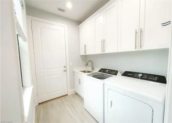 Laundry room featuring visible vents, a sink, washer and dryer, cabinet space, and baseboards