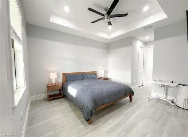 Bedroom with baseboards, visible vents, recessed lighting, light wood-style floors, and a raised ceiling
