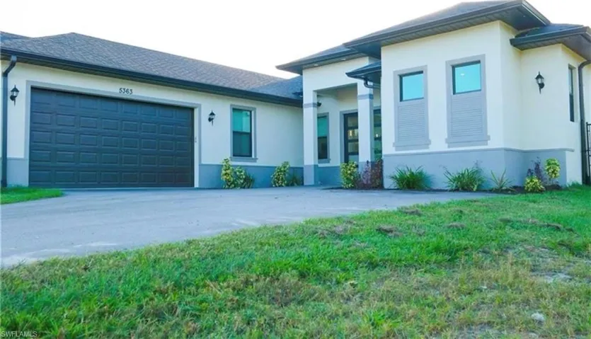 Prairie-style house with stucco siding, an attached garage, and driveway