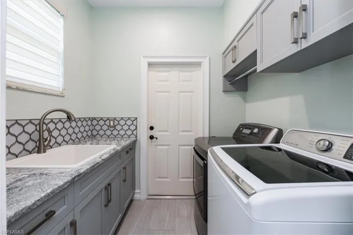 The laundry room features designer cabinets, a washing machine, a clothes dryer, and a sink right off the two-car garage, where sandy clothes can be dropped on the way in from the beach.